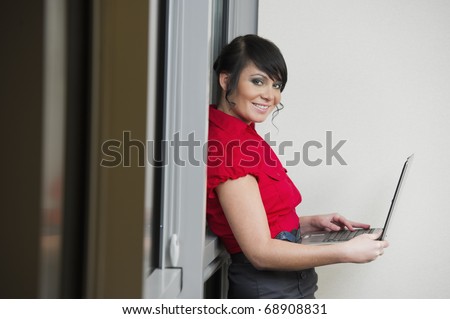 Woman with the red dress in the office with a laptop