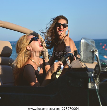 Happy beautiful young girls sitting laughing in beach truck car in sunglasses on sunny summer day.