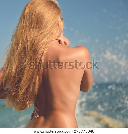 Woman looking to the sea ocean from the back naked with windy hair