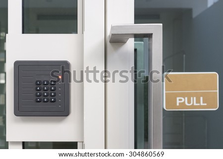 electronic access control door box with numeric keypad next to white aluminum frame glass door with sign