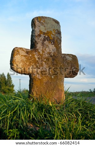Stone cross standing at road. Pskov region. Russia.