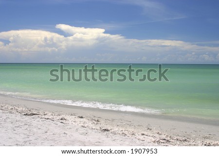 Gentle waves lap against a white sand beach on a sunny day
