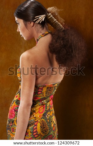 Woman in ethnic dress in the studio from the back