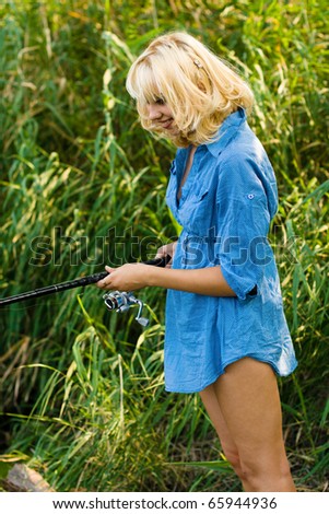 a woman fishes in the river fishing-rod. on a background a river reed