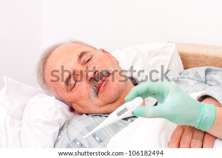 Elderly man laying in bed, nurse taking temperature.