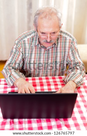 Elderly man using the laptop at home.