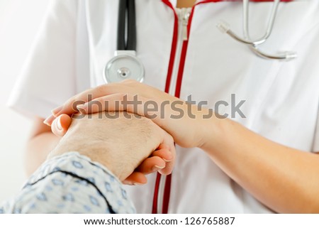 Young doctor/nurse holding elder patient\'s hand with care.