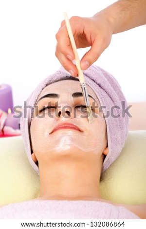 Attractive lady at spa relaxing while receiving facial mask.