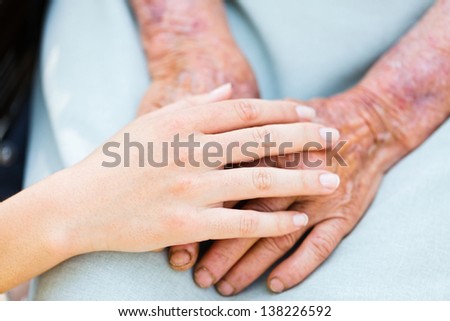 Caring woman hands over elderly hands being concept of trust and reliability.