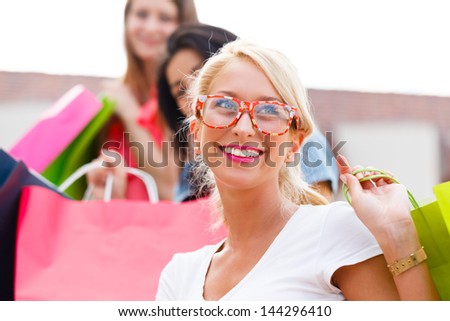 Laughing young woman with friends shopping in town.