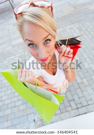 Woman with big blue eyes holding shopping bags.