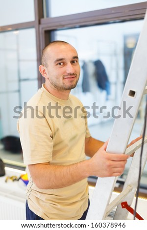 Smiling electrician man holding ladder starting the work.