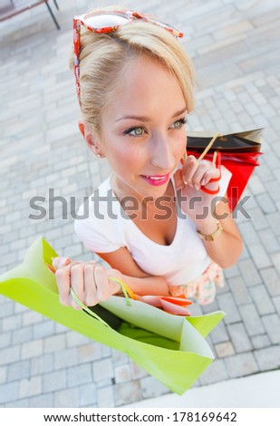 Attractive young blond lady holding shopping bags.