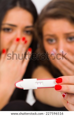 Scared teenager girl showing a positive pregnancy test.