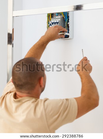Electrician man installing electric fuse at home.