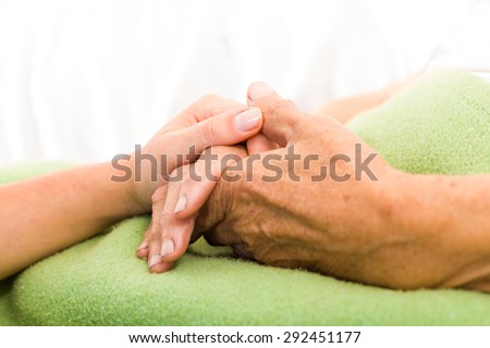 Health care nurse caring for elderly concept - holding hands.