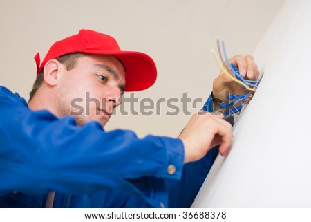 A young electrician insulating electric wires of an electric box.