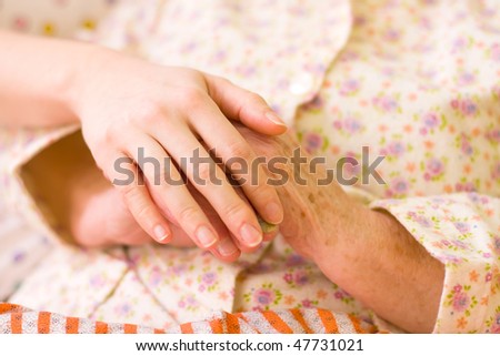 A young hand holding an elderly one. It can be a hand of a carer or a family member.