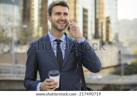 Business man talking on a cell phone smiling downtown