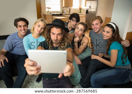 Friends together taking a photo selfie on a tablet to share on social network