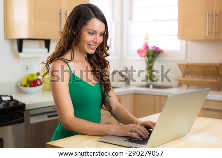 Pretty woman on her laptop looking up recipe to cook in the kitchen