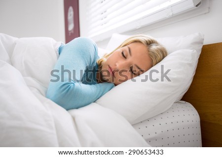 Woman in bed with eyes closed peacefully resting and sleeping taking a nap