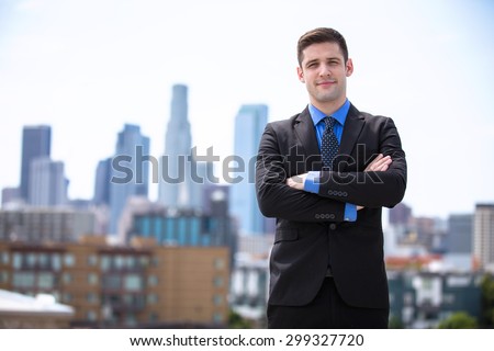 Young business man attorney arms folded proudly standing in the city building background
