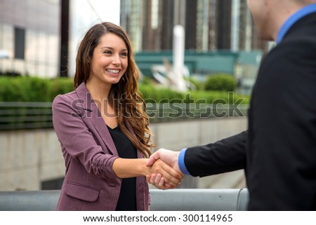 Handshake two business executives downtown buildings man and woman perfect smile teeth hair skin