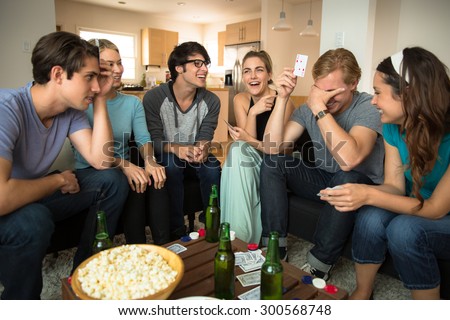 Young group of friends attractive people laughing embarrassed poker player card game night loser winner