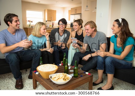 Attractive group of friends at home game night party popcorn beers card playing poker