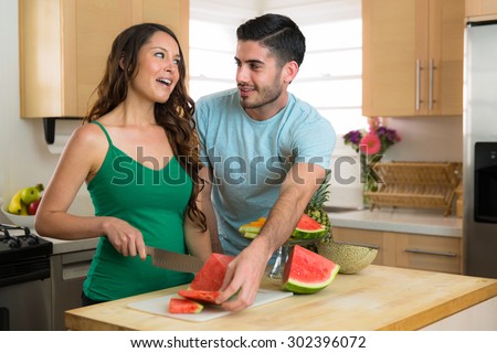 Playful couple lifestyle chopping fruits and vegetables watermelon laughing in kitchen