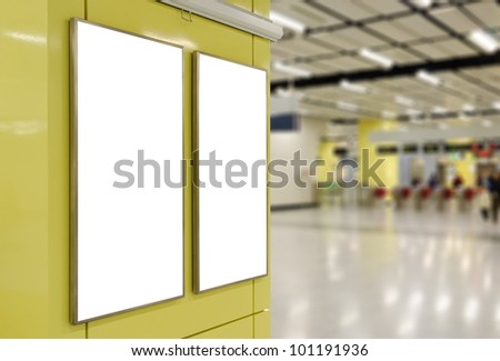 Two big vertical / portrait orientation blank billboard on modern yellow wall with entrance of railway station background