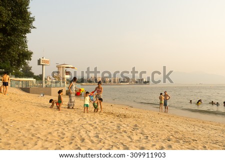 HONG KONG - AUG 25, 2015: Unidentified group of people having fun at the Gold Coast Beach in sunset, Hong Kong. Gold Coast Beach is one of popular beach in Hong Kong.