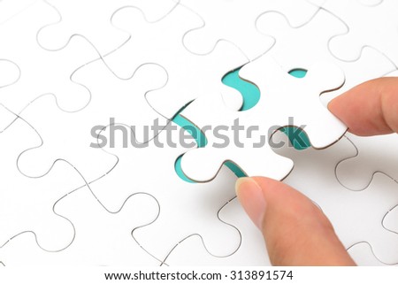 Person's hand completing last piece of Jigsaw puzzles