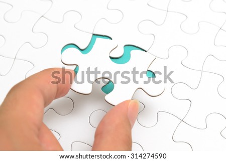 Person\'s hand completing last piece of Jigsaw puzzles