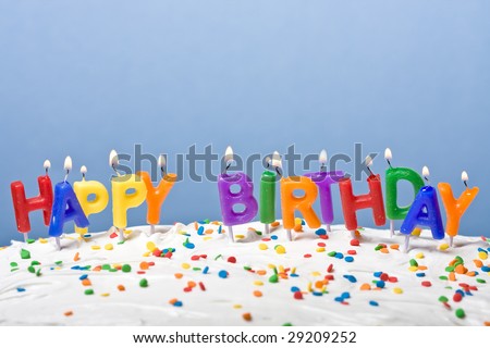 lit candles on a white frosted cake blue background