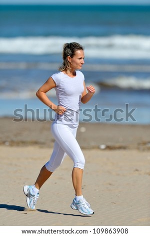 young woman jogging on the beach in summer