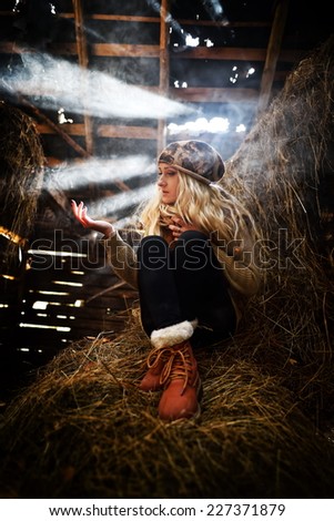 Beautiful woman relaxing in straw in autumn in smoky, dusty room