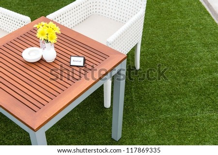 Tropical wooden dinning table on green grass with reserve sign on the table, taken on a cloudy day