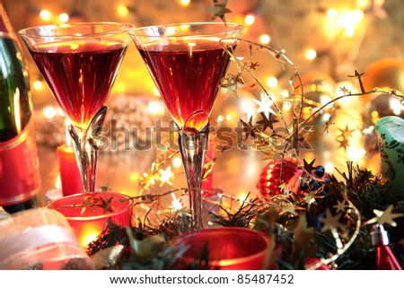 Closeup of red wine in glasses, bottle and candle lights on golden background with twinkle lights.