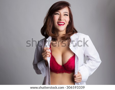 Sexy asian woman showing her sexy breast in red bra, looking up, with shirt opened by her hand