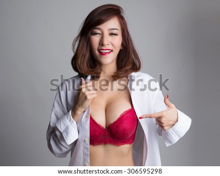Sexy asian woman showing her sexy breast in red bra or  lingerie with hand pointing at her breast, shirt opened by her hand