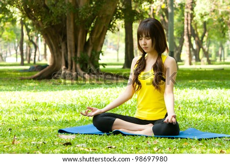 Young asian woman doing yoga in beautiful green park