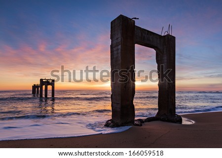 The ruins of an old concrete pier near Davenport, California on reaching out into the Pacific Ocean during Sunset.