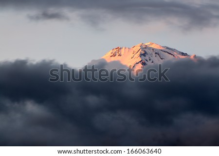 Sunset sets Shasta Mountain aglow as it rises above a late winter storm.