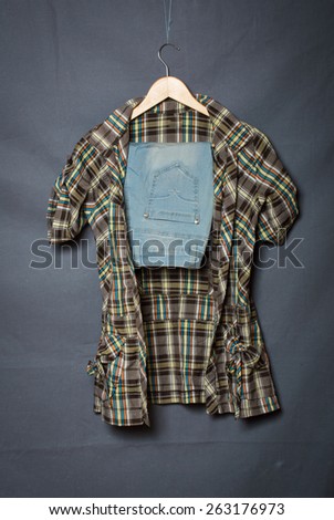 jeans and a shirt on a hanger on a gray background