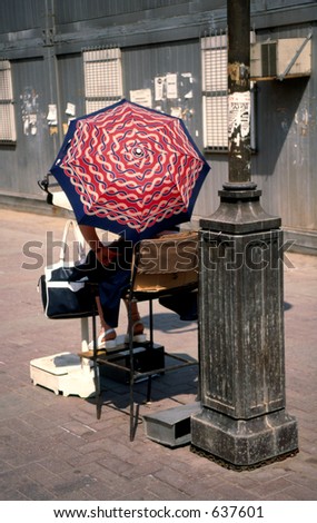 The person hiding under a umbrella from the sun