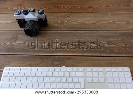 top view of a desktop of a photographer consisting on a camera and keyboard on a dark desk background - suitable for copy space