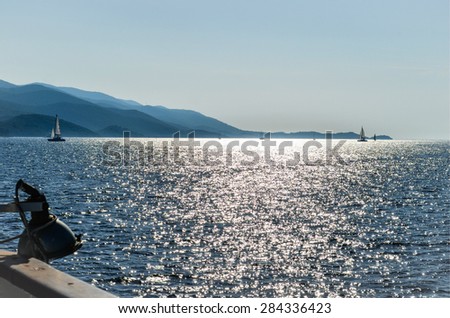 Beautiful sunset seen from sailing boat, with shining sea, yachts and mountains. Summer background