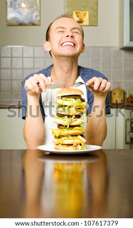 happy young man is going to eat big layered cheeseburger